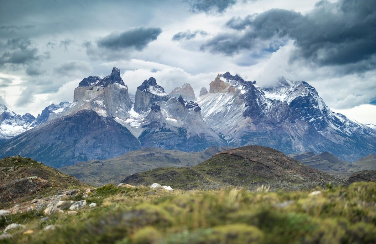 Sweeping view of Torres del Paine mountain range in Patagonia Chile with dramatic clouds and wild grassland