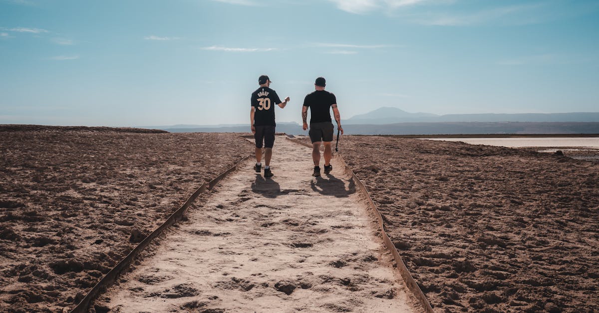 Two men walking along a sandy path in the vast Atacama Desert, Chile, under a clear sky