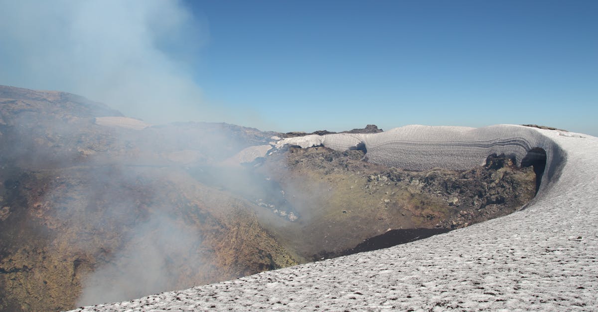 View of Villarrica Volcano's snowy crater emitting smoke under clear blue skies in Chile