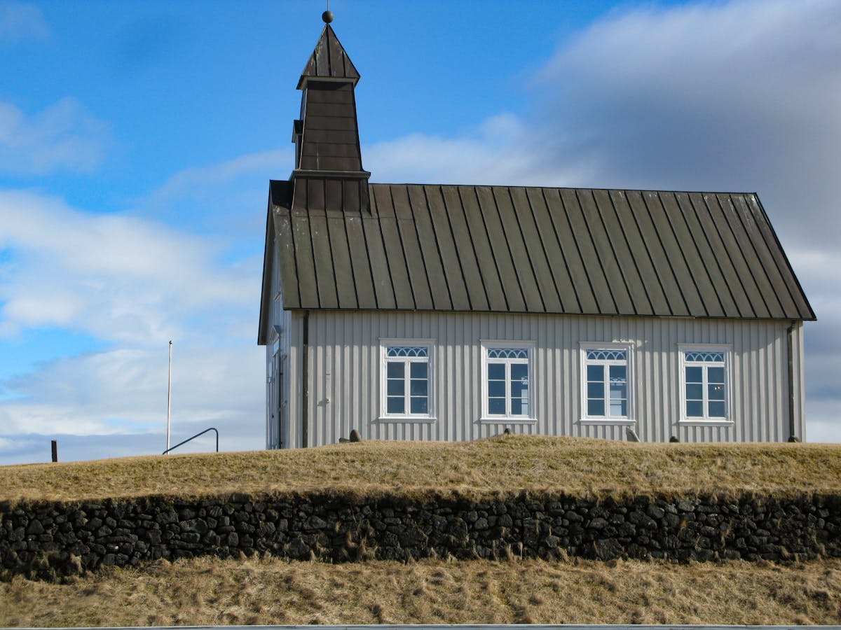 Historic wooden church with tall steeple and timber construction against a blue sky