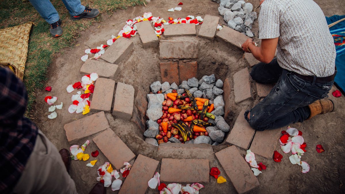 Traditional underground earth oven with vegetables and ingredients for cooking