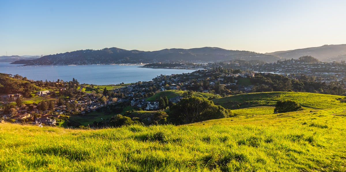 Panoramic view of a coastal town surrounded by green hills and calm sea
