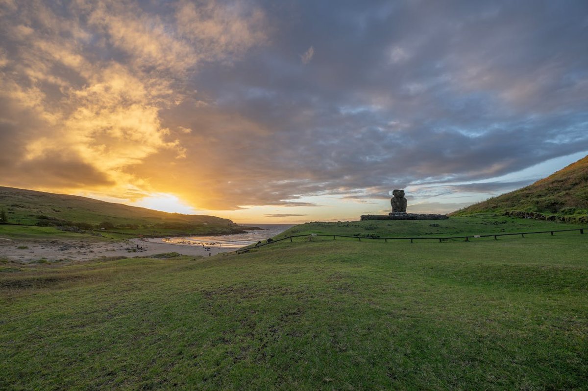 Moai statue silhouetted against a colorful sunset sky at Ahu Tahai on Easter Island