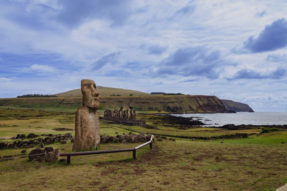 Moai statue on Easter Island coastline with rocky cliffs and grassy plains in background