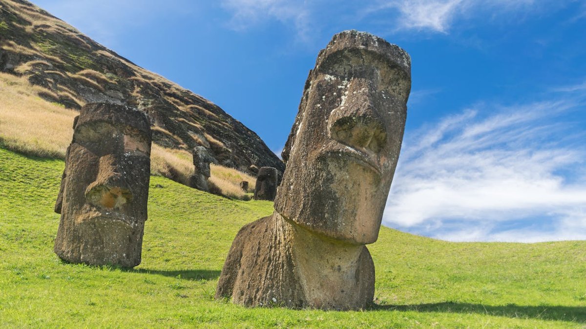 Half-buried moai statue emerging from the ground on Easter Island with dramatic sky above