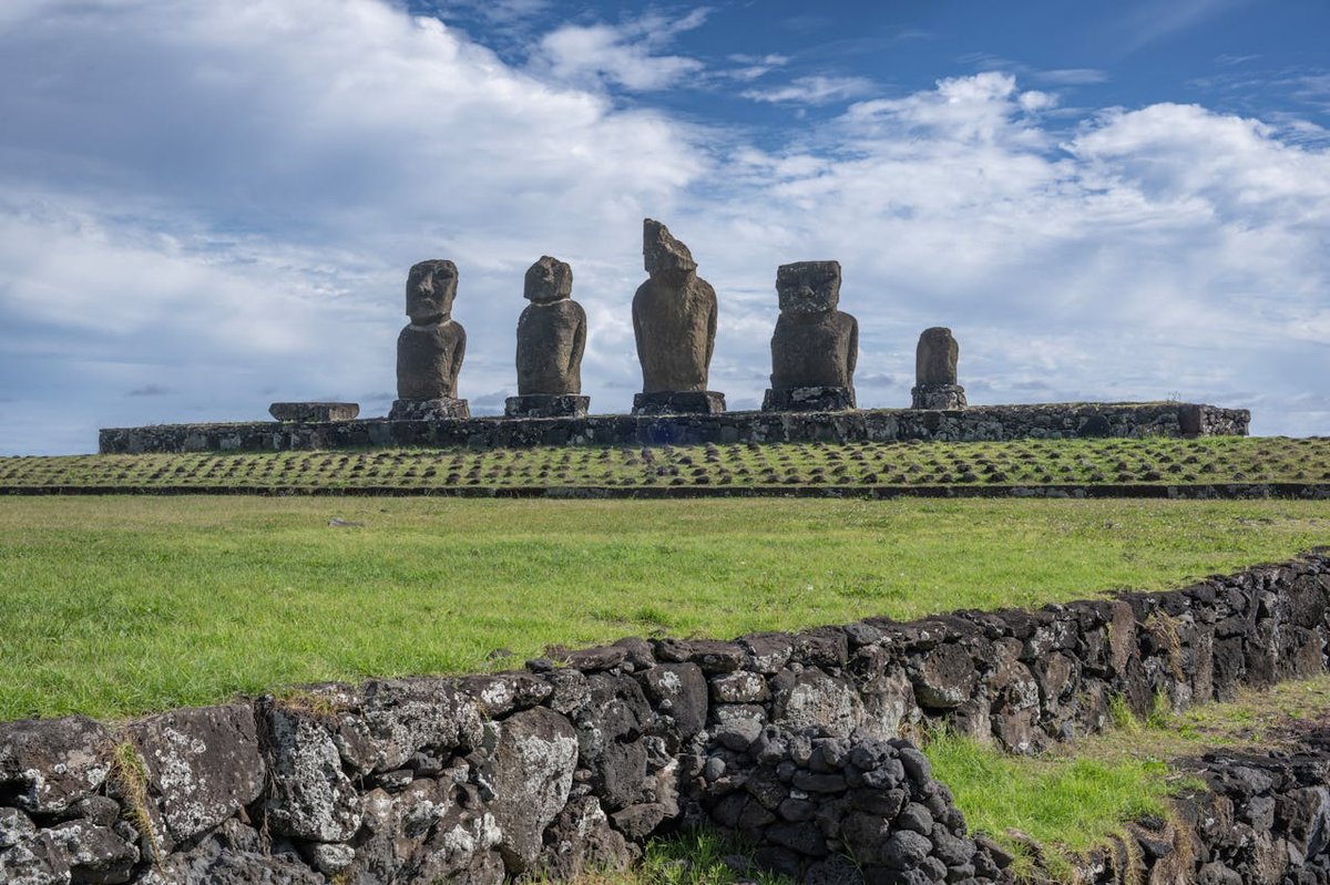 Row of moai statues standing in formation on Easter Island under clear blue skies