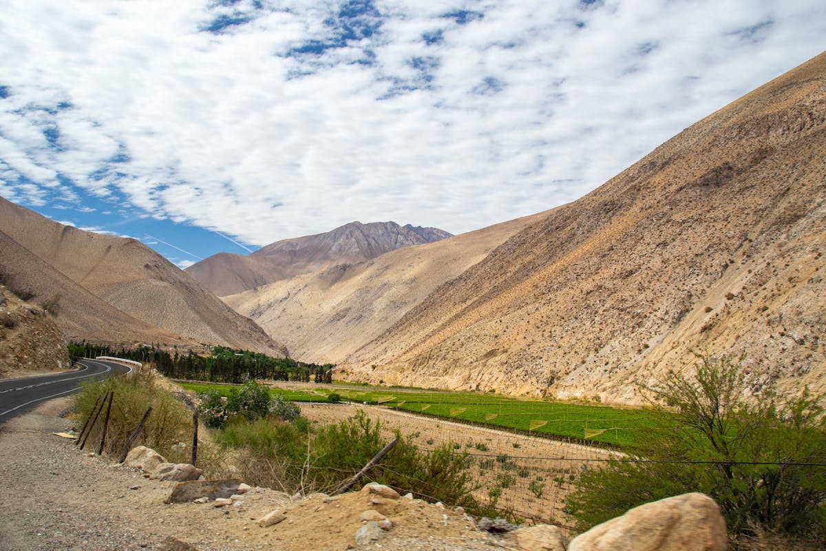 Elqui Valley in Chile showing brown mountain ridges and green irrigated fields under a cloud-dappled sky