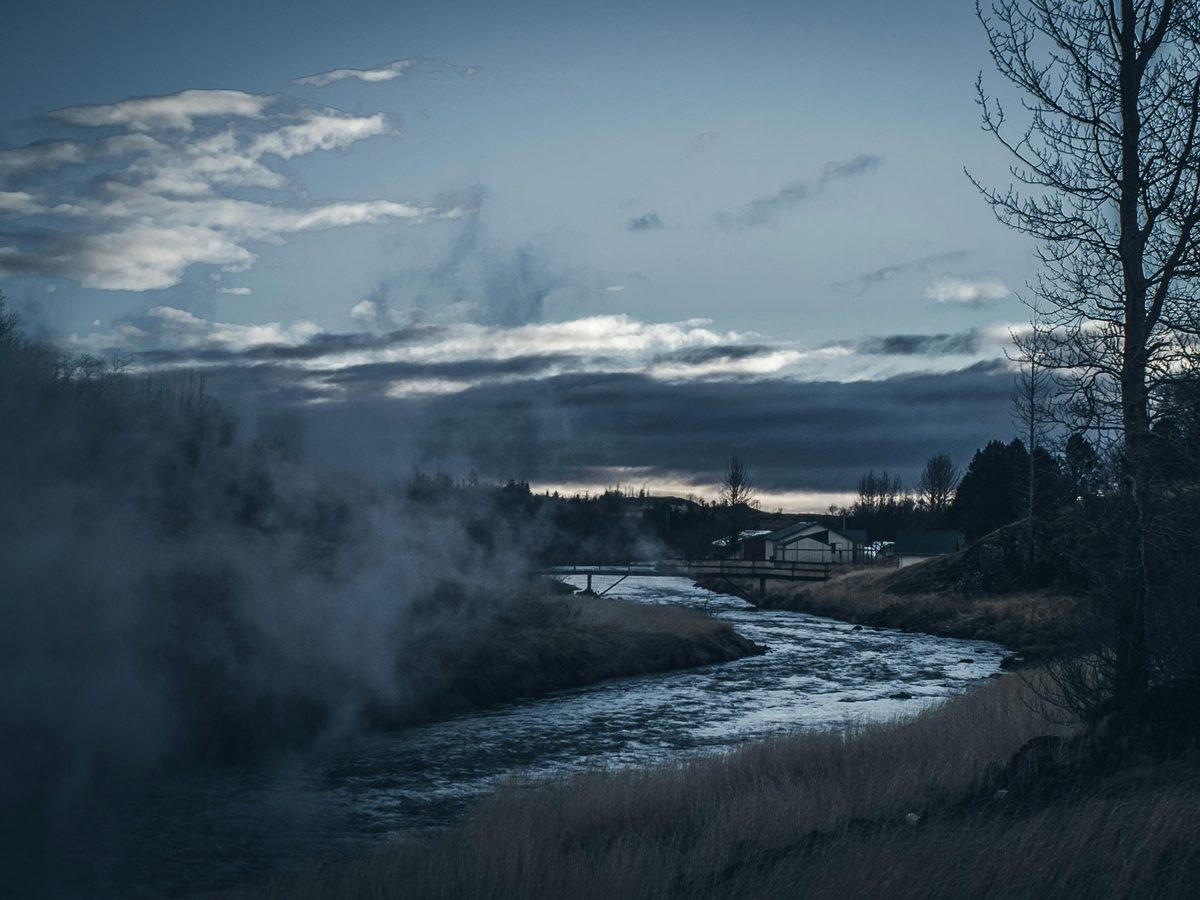 River flowing through a green valley with steam and mist at twilight