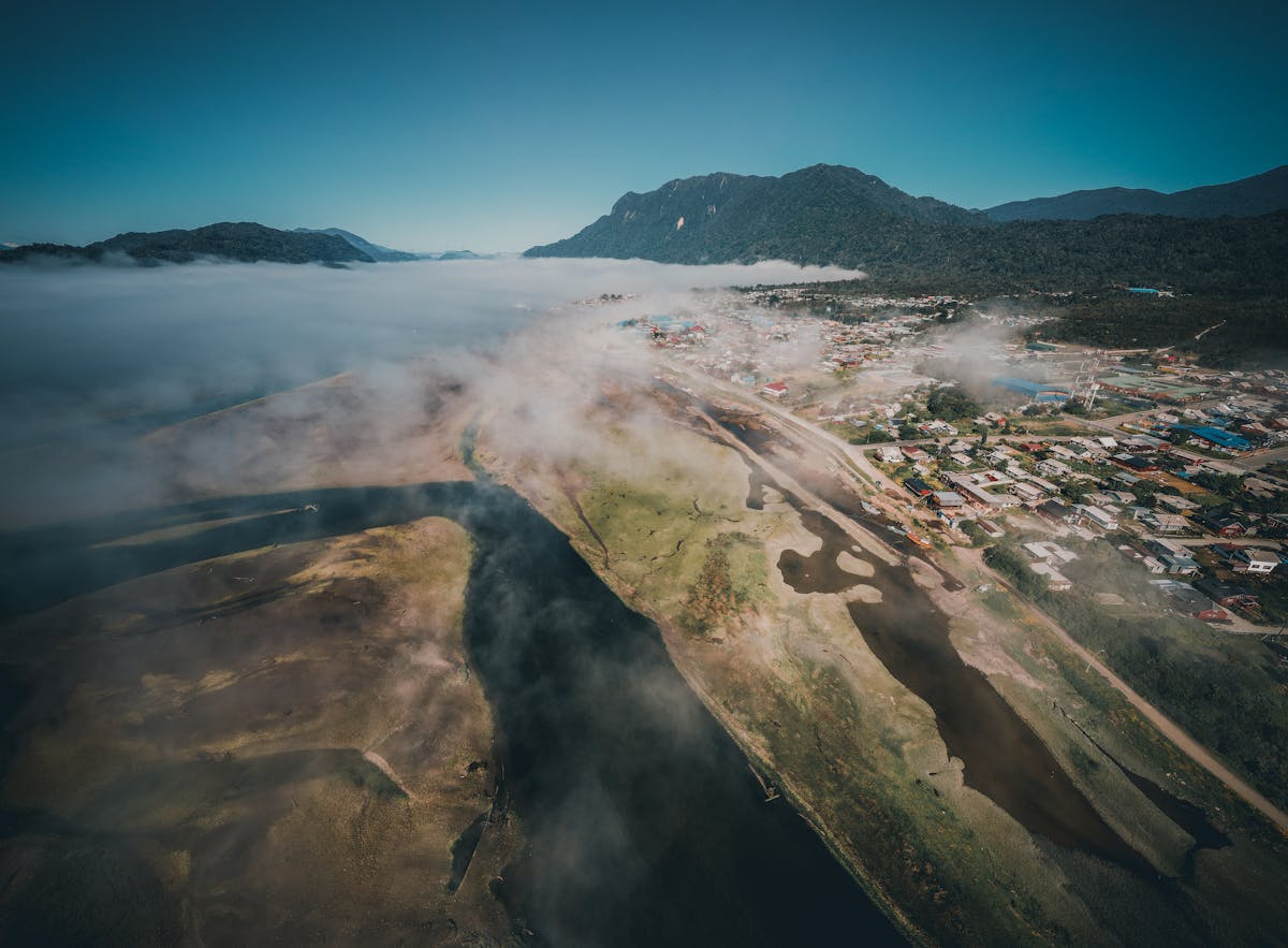 Aerial view of mist-covered mountains and river in the Chilean fjords near Hornopiren