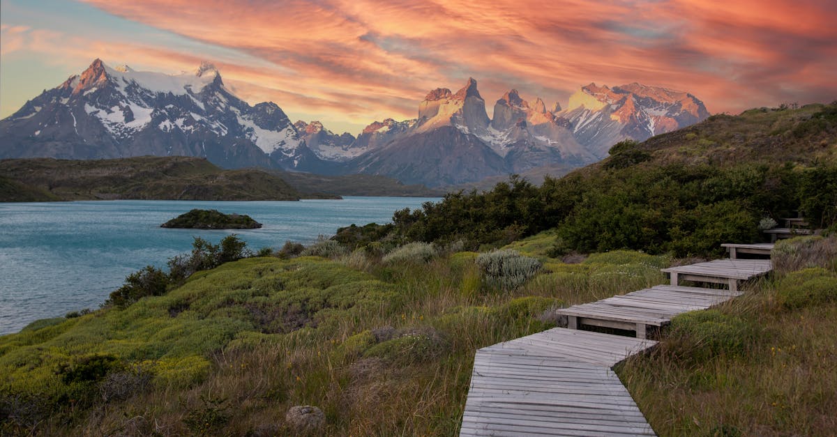 Wooden boardwalk leading toward Torres del Paine mountains under a vivid sunset sky