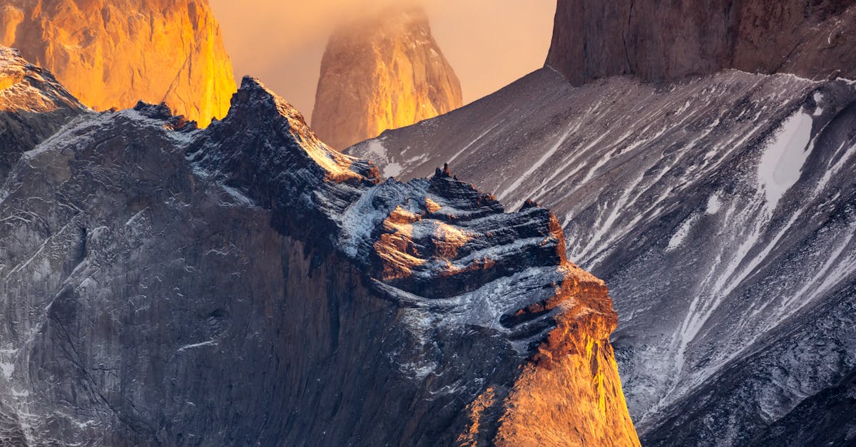 Sunrise illuminating the rugged peaks of Torres del Paine with dramatic warm light and morning mist
