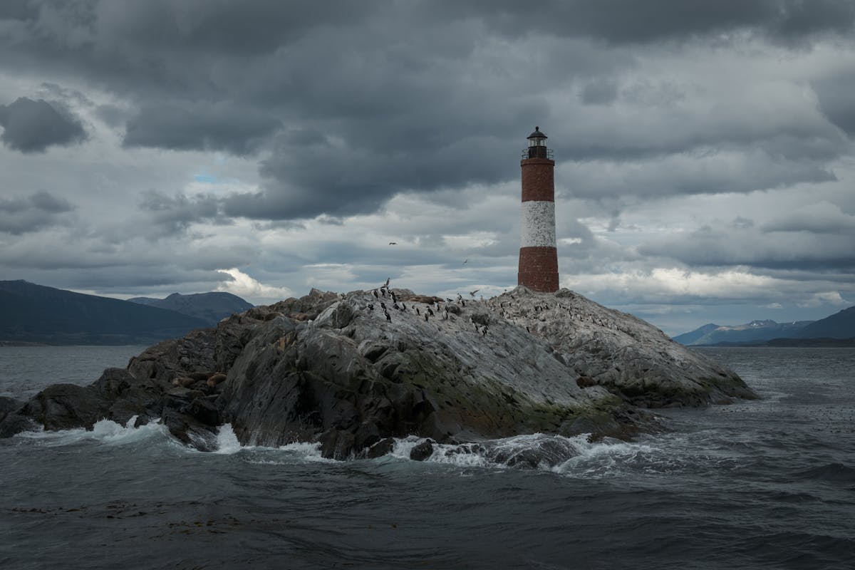 Les Eclaireurs Lighthouse on rocky island near Ushuaia under dramatic sky