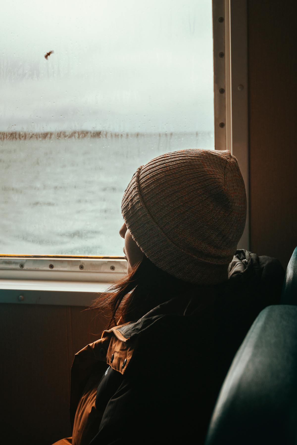 Traveler looking out the window of a ferry crossing the Strait of Magellan in Chile