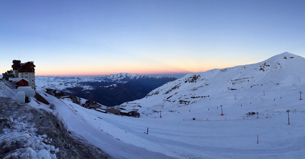 Snow-covered Andes mountain slopes with ski runs and dramatic sunset light