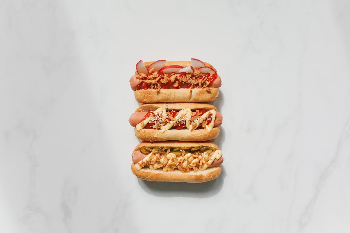 Gourmet hot dogs with various toppings on a white surface