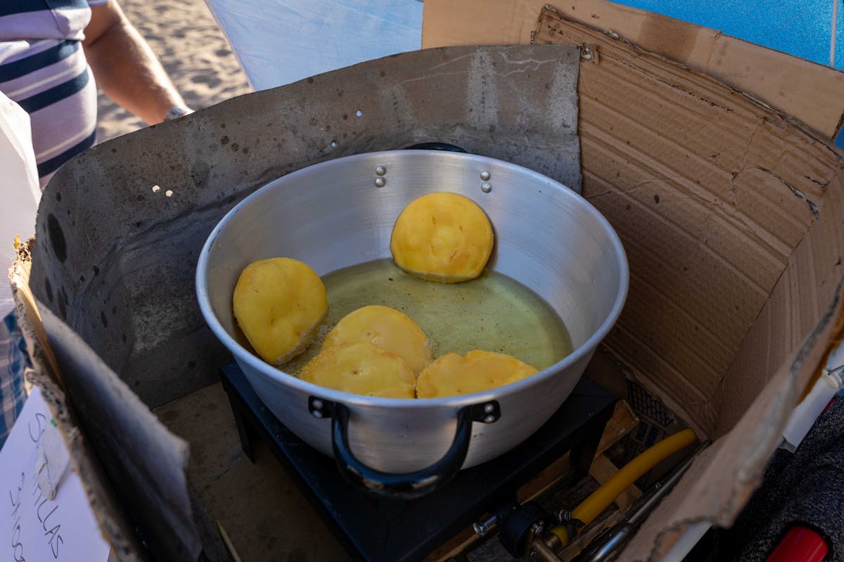 Sopaipillas frying in a pan at a street market stall in Chile