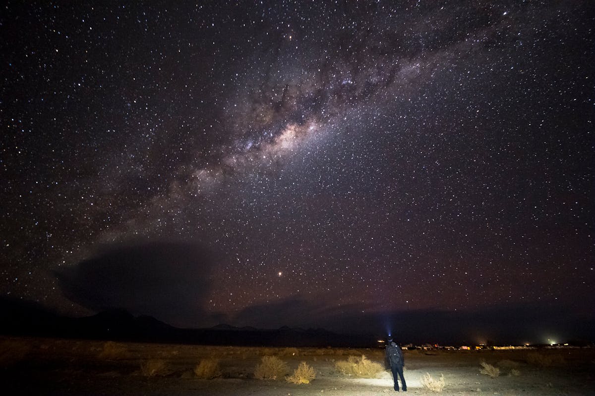 A person standing alone under the Milky Way in the Atacama Desert Chile at night gazing at stars