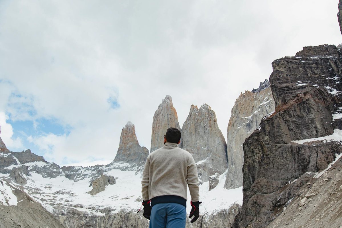 Hiker on trail in Torres del Paine with snowy mountain peaks in the distance