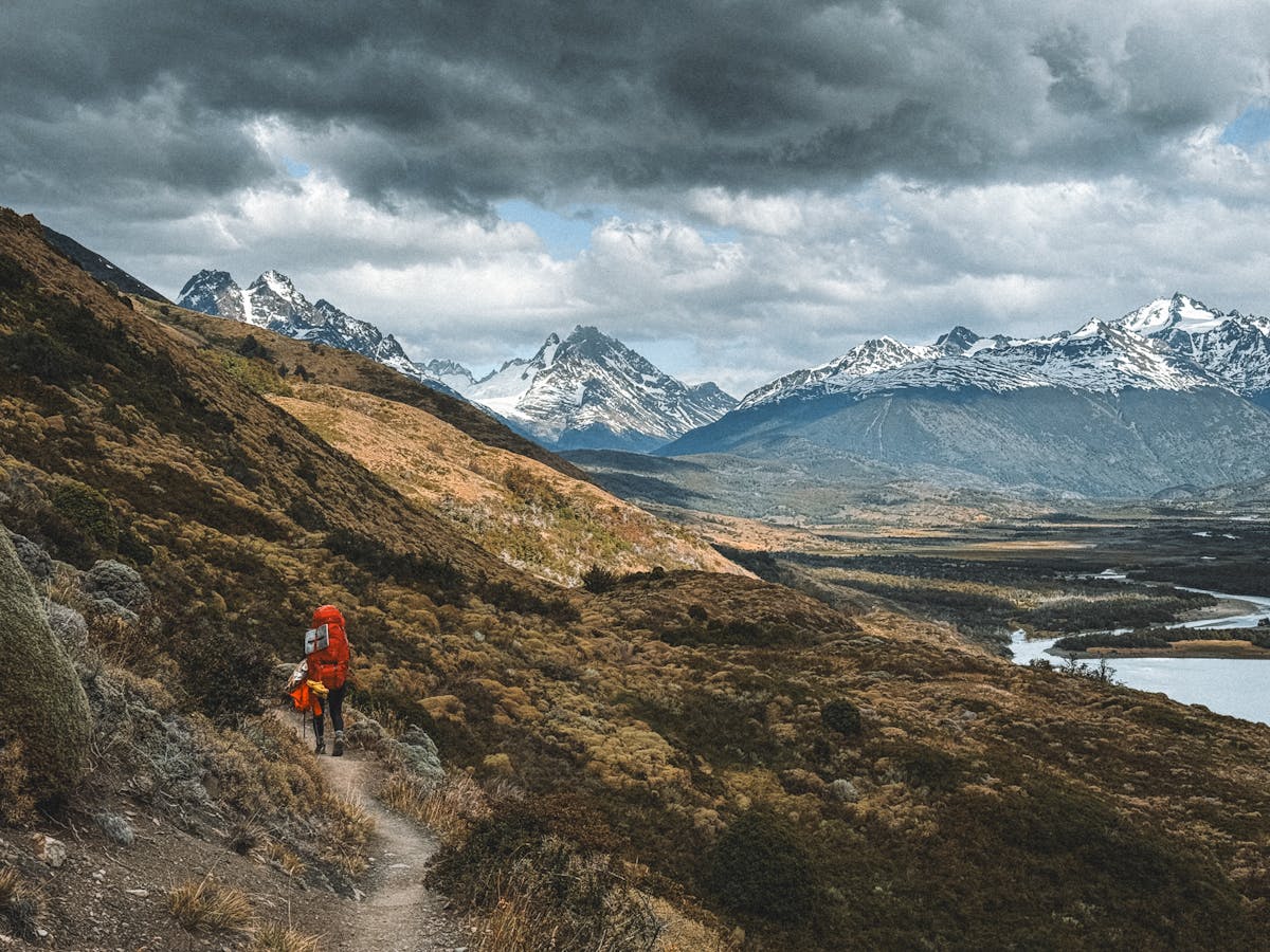 Solo hiker trekking through the mountains of Magallanes, Chile with dramatic skies overhead
