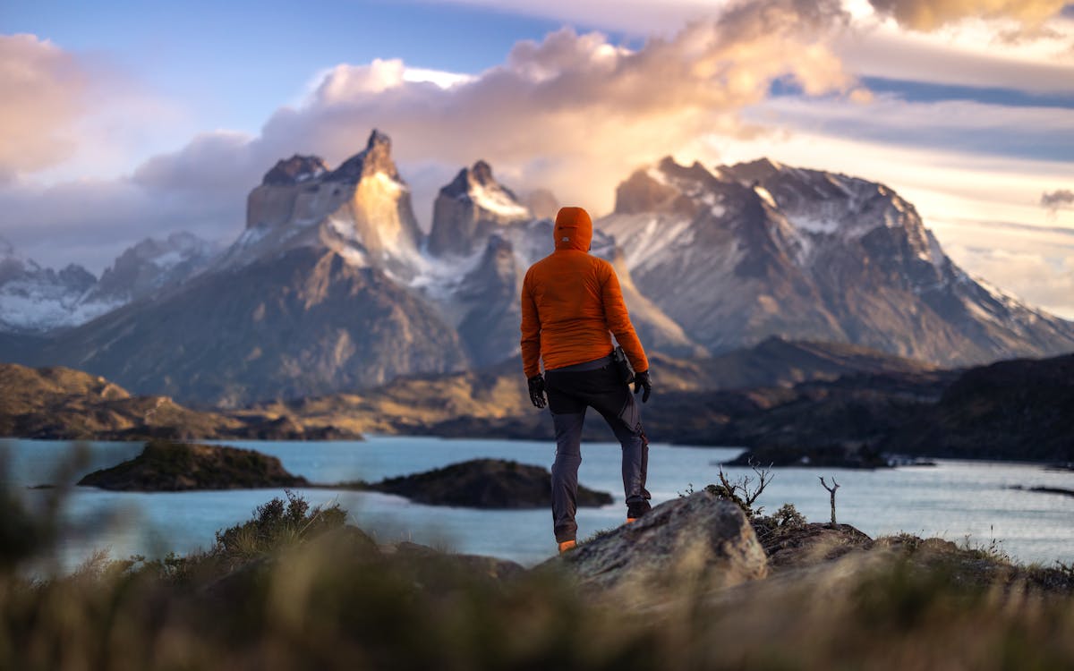 Hiker at sunrise in Torres del Paine overlooking mountains and a tranquil lake