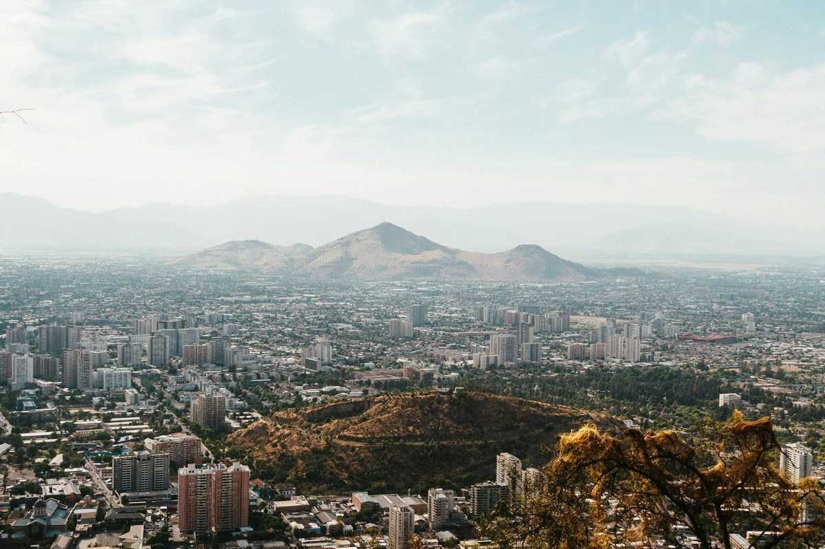 Aerial view of Santiago, Chile with mountains in the background and cityscape below.