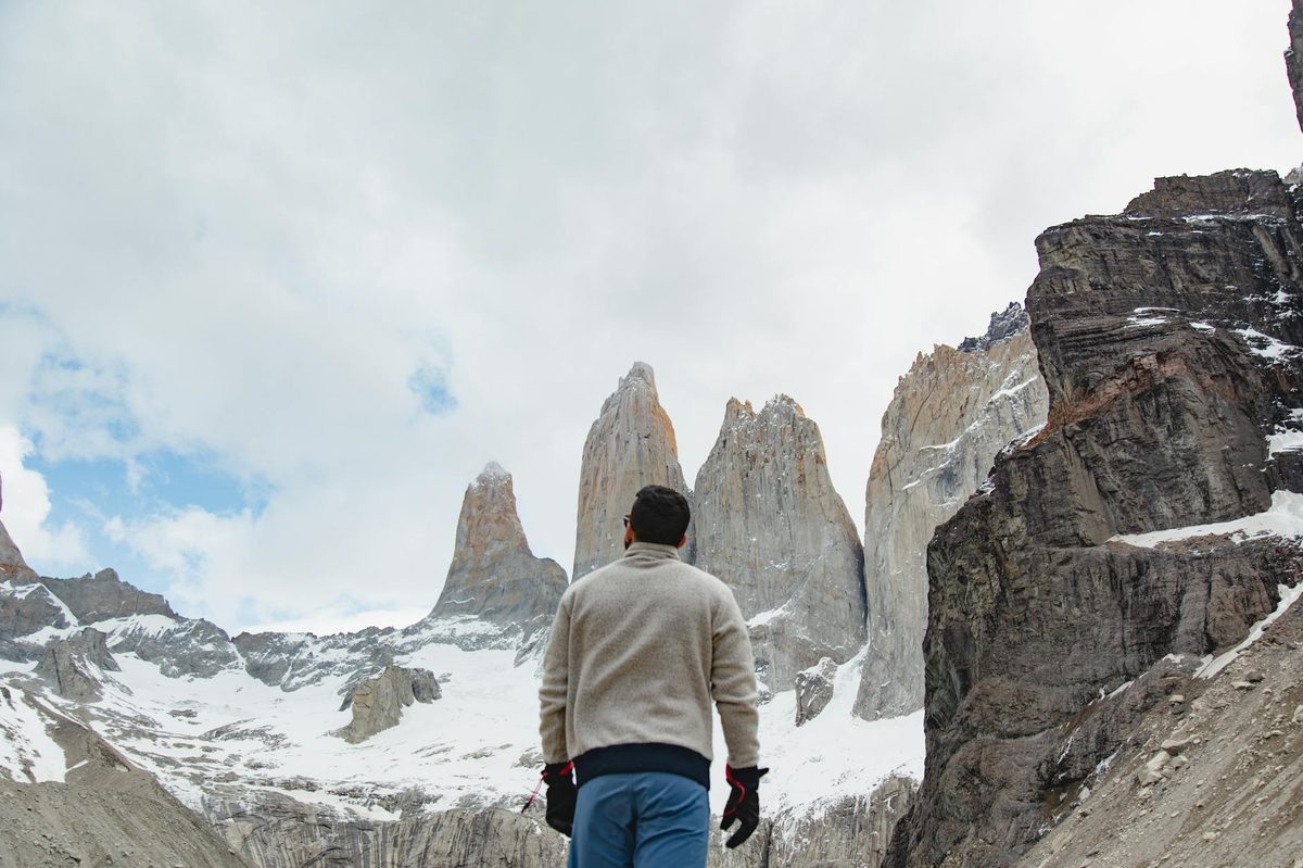 Man hiking in Torres del Paine National Park with snowy mountain peaks in view.
